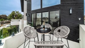 Un balcon avec une table dressée pour deux personnes, agrémenté de chaises en osier et d’une bouteille de champagne.
