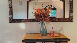 A mirror with a decorative wooden frame, a vase with dried flowers, and a table with a woven placemat. - La Cafecito Bistro and accommodation  (Kigali)
