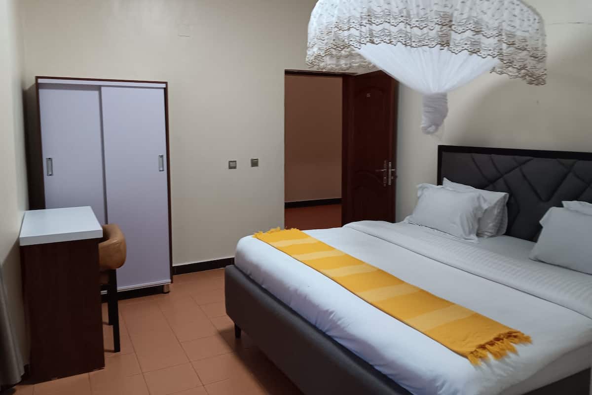 A bedroom with a bed, a wardrobe, a desk, and a chair.