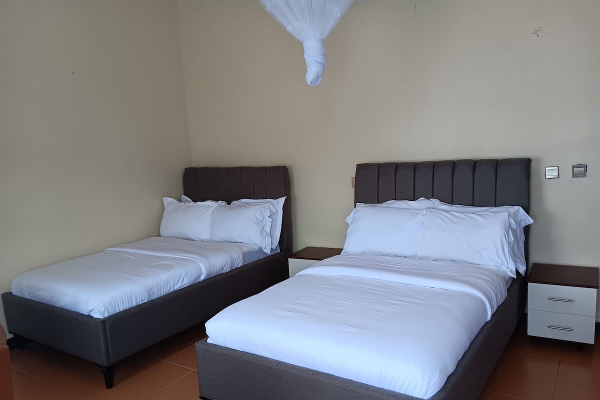 A hotel room with two single beds, each with a dark headboard and white bedding.