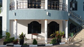 A multi-story building with a curved facade, balconies with metal railings, and a staircase leading to an upper level. - La Cafecito Bistro and accommodation  (Kigali)