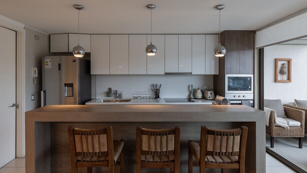Uma cozinha moderna com ilha central, iluminação pendente e cadeiras de madeira.