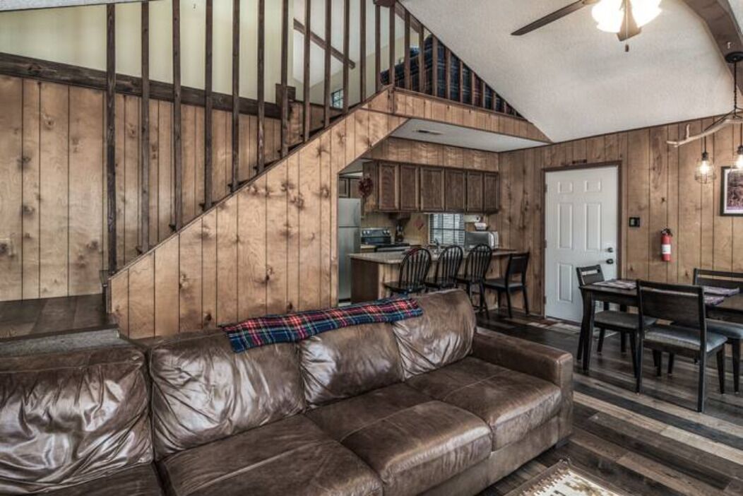 Ein rustikales Interieur mit Ledersofa, einer Holztreppe und einer Küchenzeile.