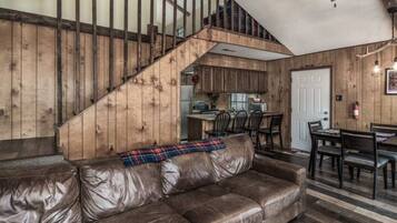Ein rustikales Interieur mit Ledersofa, einer Holztreppe und einer Küchenzeile.