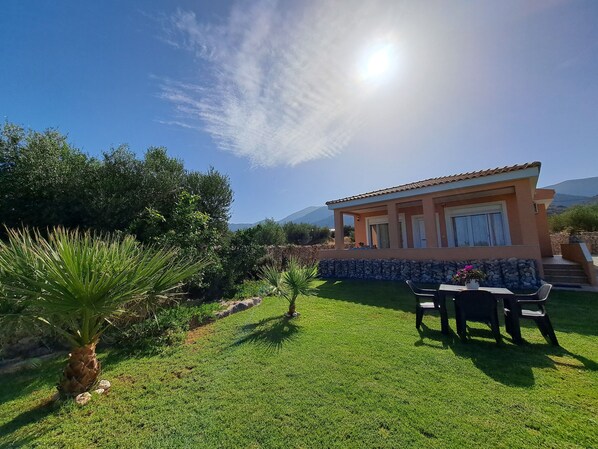 A house with a patio, a stone wall, and a view of mountains.