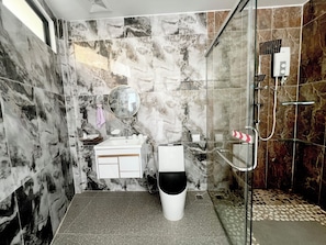 Ein Badezimmer mit Marmorwand, Waschbecken, Toilette und Dusche.