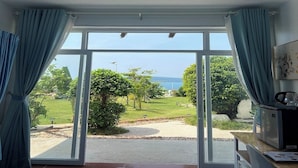 Una habitación con un amplio ventanal corredera que da a un jardín con vista al mar.