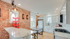 A kitchen with a brick wall, white cabinets, a granite countertop, and a gas stove. - 15 Mi to Amish Village: Cozy Lancaster Apt! (Lancaster)