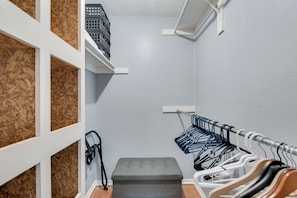 A storage closet with shelves, a step, and a clothing rack.