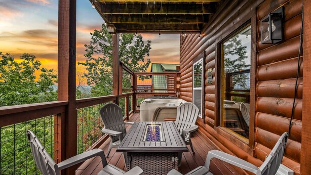 Una terraza de madera con una mesa y sillas, un jacuzzi y vistas al atardecer.