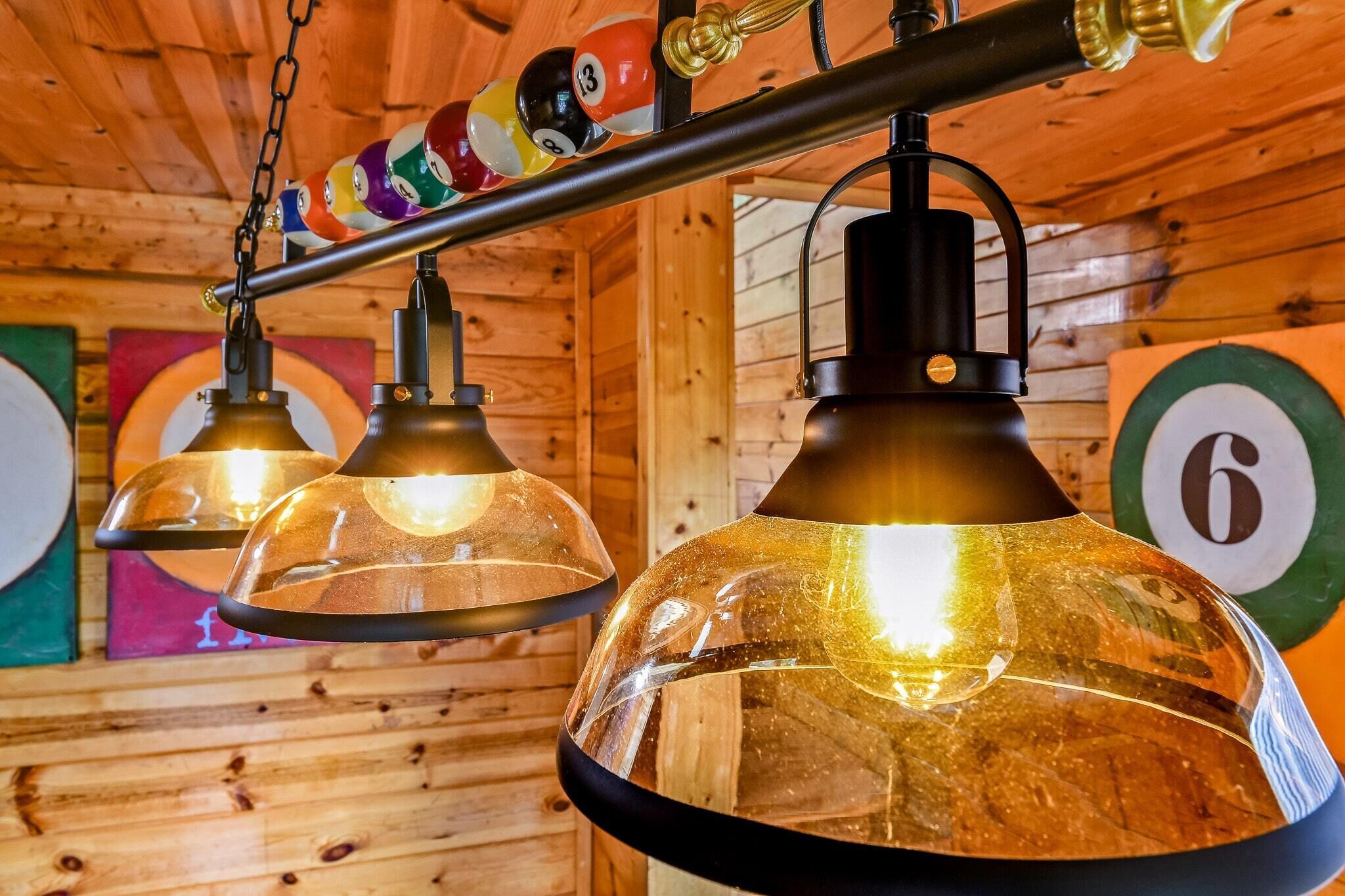 A wooden interior with hanging pendant lights and colorful billiard balls on a rack.