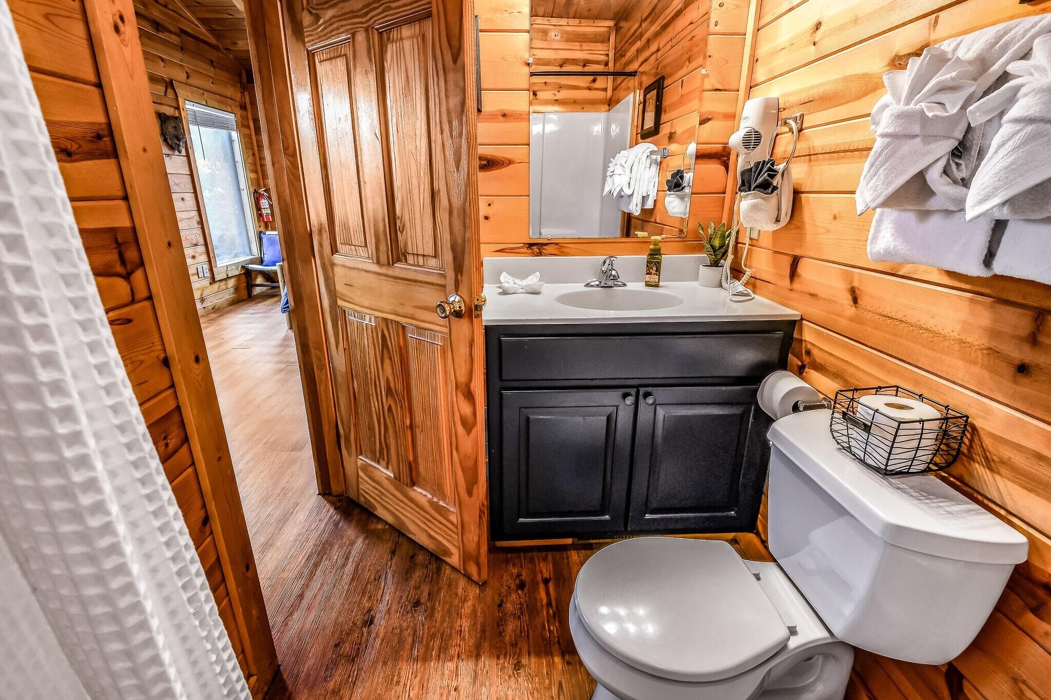 Ein Badezimmer einer Holzhütte mit Toilette, Waschbecken und Spiegel.