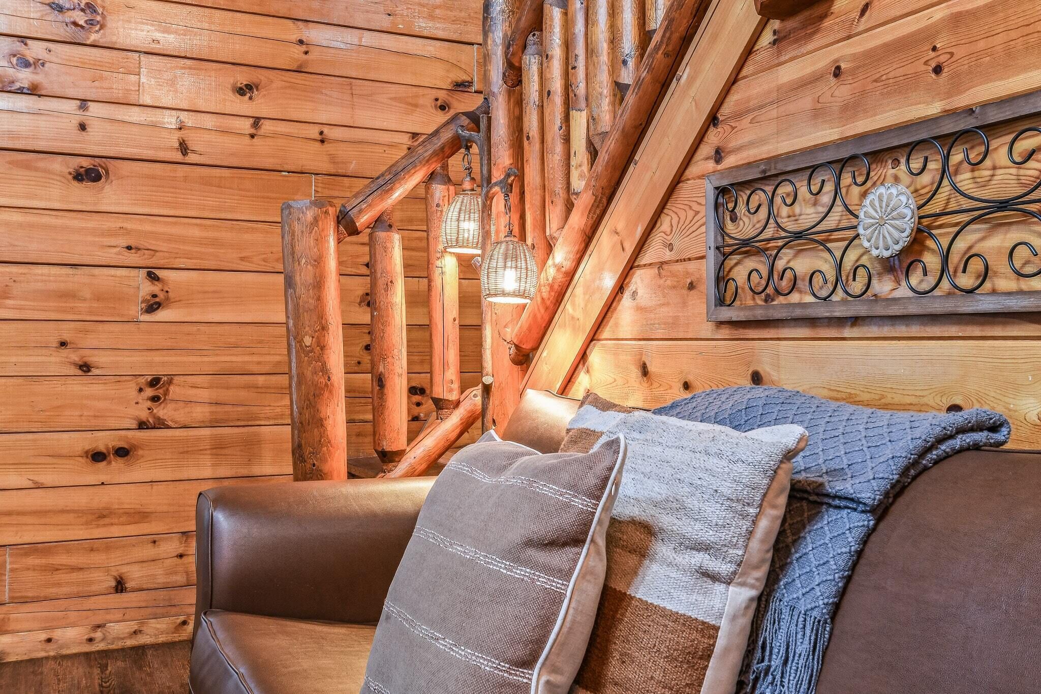 A wooden cabin interior with a wooden staircase, a cushioned bench, and a decorative metal piece on the wall.