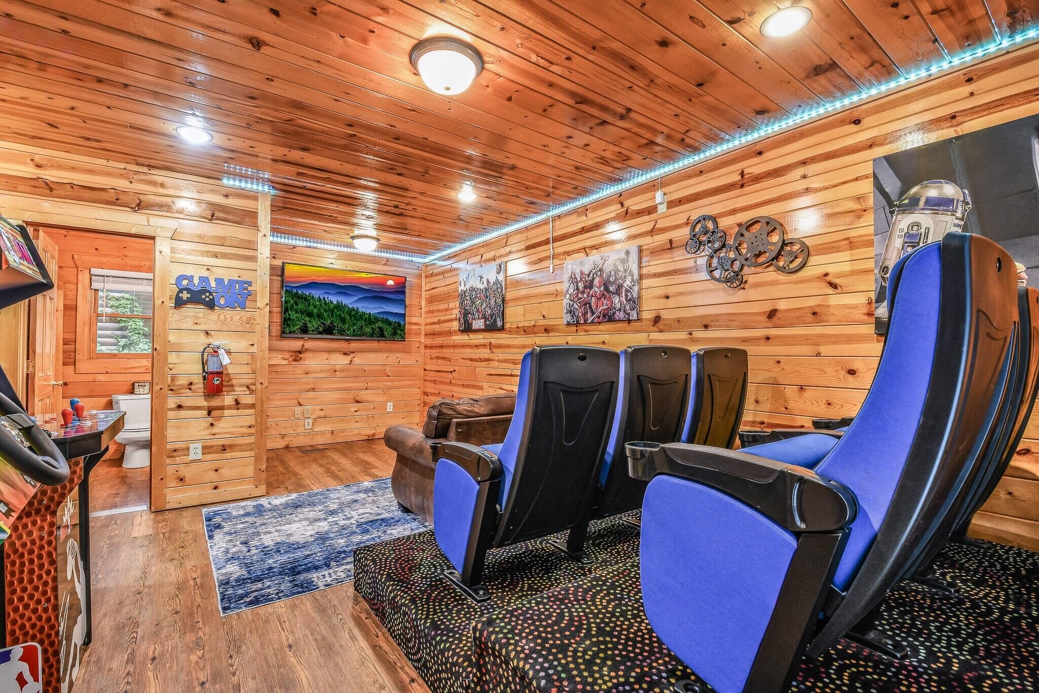 Un intérieur en bois avec une enseigne indiquant « salle de jeux », des chaises bleues et des œuvres d’art accrochées aux murs.