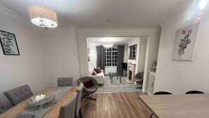 A modern living room with a dining area, a fireplace, and a large window. - Charming Central Torquay Cottage (Torquay)