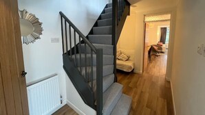 A staircase with a modern design, a wooden door, and a white radiator. - Charming Central Torquay Cottage (Torquay)
