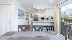 Une cuisine moderne avec des meubles blancs, un îlot central et une grande fenêtre.