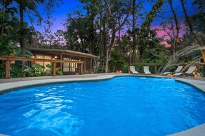 A swimming pool with lounge chairs and a building with large windows. - Whispering Woods Cottage - A Tranquil Escape (Jupiter)