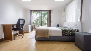 A bedroom with a bed, a desk, a chair, and a window with curtains. - Cosy, personal, family-friendly nature retreat surrounded by trees and fresh air (Aburi)