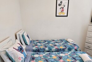 A bedroom with two beds, each with a colorful bedspread featuring cartoon characters. There is a framed picture of a cartoon character on the wall above the beds. - Disney 10-Min Drive! Resort Condo w/ Pool & (Kissimmee)