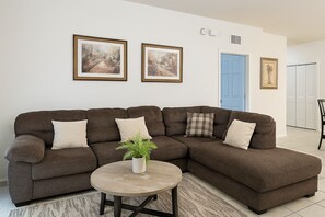 Una sala de estar con un sofá modular, una mesita redonda y dos cuadros en la pared.