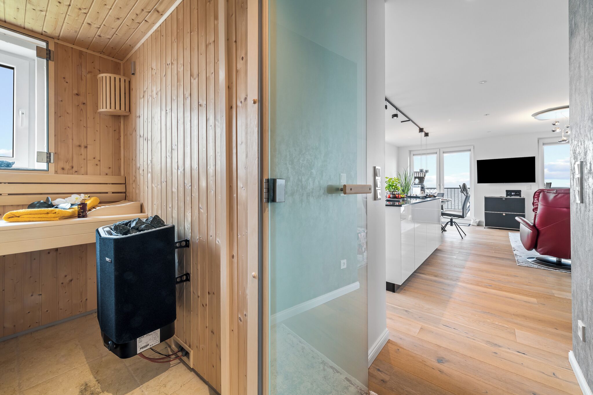 A modern kitchen with a large island, a built-in oven, and a flat-screen TV.