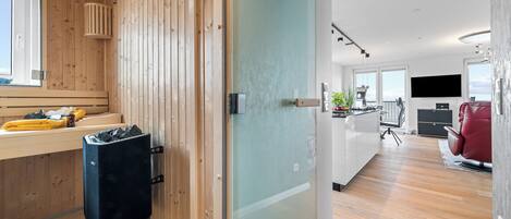 A modern kitchen with a large island, a built-in oven, and a flat-screen TV.