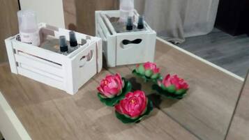 A wooden table with white storage boxes and pink artificial flowers.