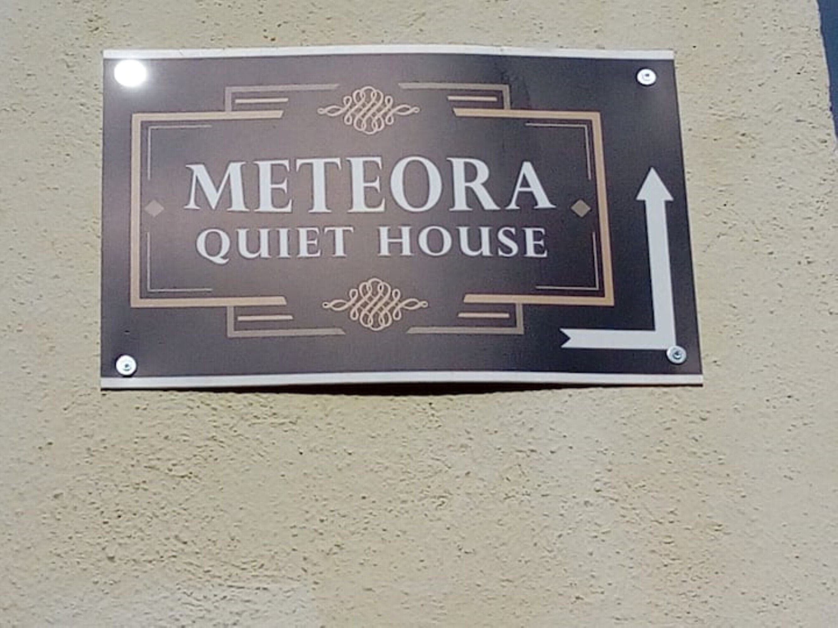 En skylt för Meteora Quiet House med en pil som pekar uppåt.