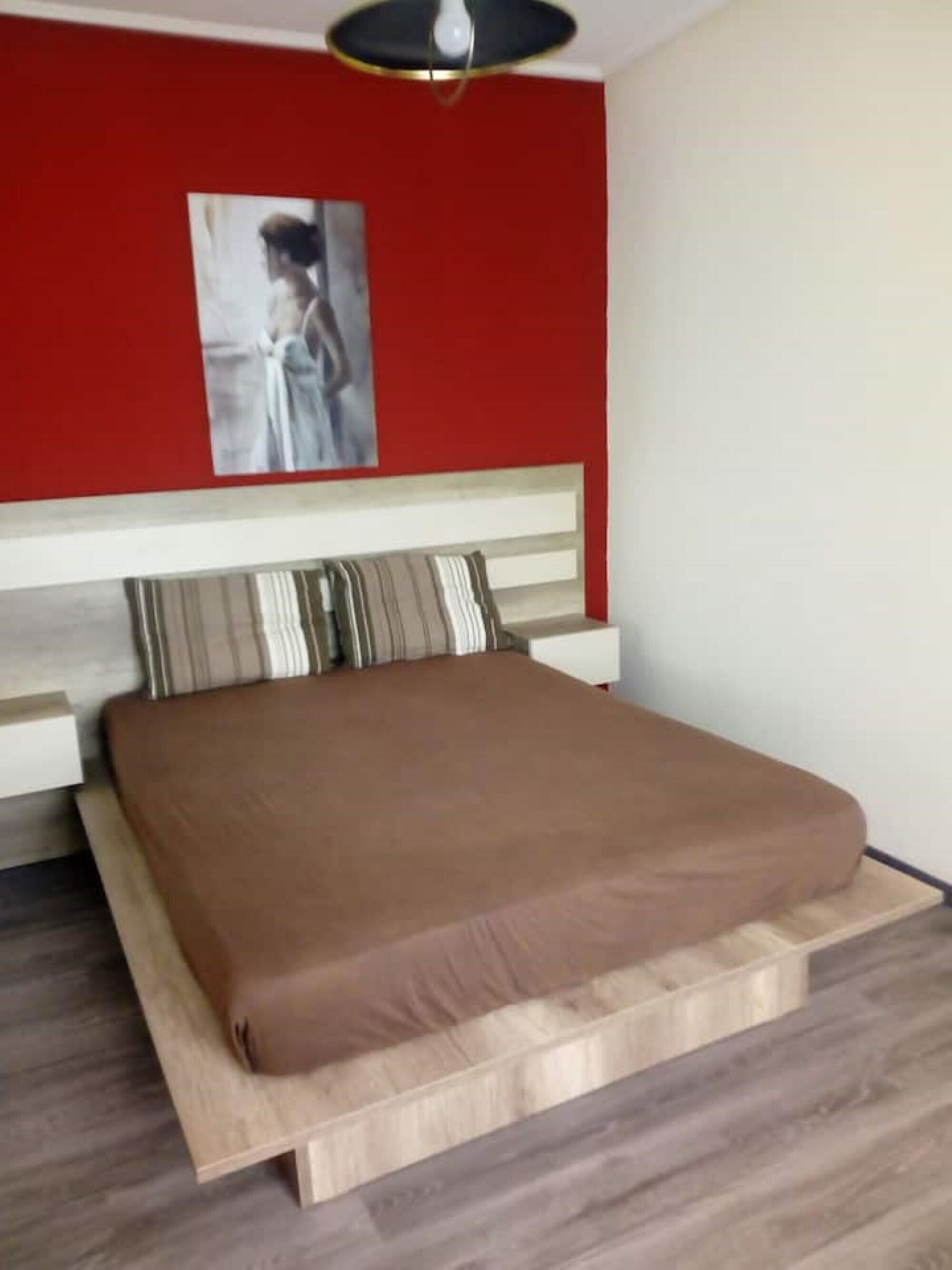 A bedroom with a bed, a headboard, and a painting on the wall.