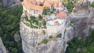 A hotel perched on a cliff with multiple buildings, surrounded by lush greenery and rocky terrain.