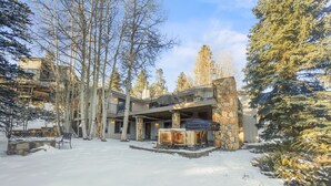 Un bâtiment en pierre à plusieurs niveaux, doté d’une cheminée en pierre et d’un espace extérieur aménagé pour s’asseoir.