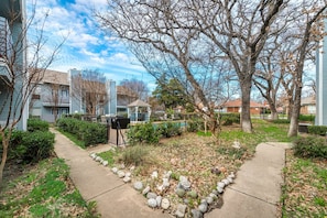 A residential area with houses, a pathway, and a small garden with rocks and plants.