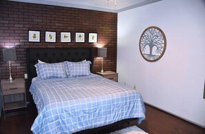 A bedroom with a bed, nightstands, a brick wall, and a wall decoration. - I10 - Apt|Patio|11mi to Convention Ctr|Sleeps 2 (Irving)