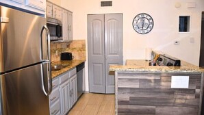 A kitchen with a stainless steel refrigerator, microwave, and granite countertop. - I10 - Apt|Patio|11mi to Convention Ctr|Sleeps 2 (Irving)