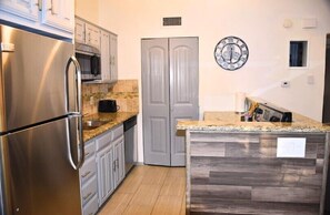 A kitchen with a stainless steel refrigerator, microwave, and granite countertop. - I10 - Apt|Patio|11mi to Convention Ctr|Sleeps 2 (Irving)
