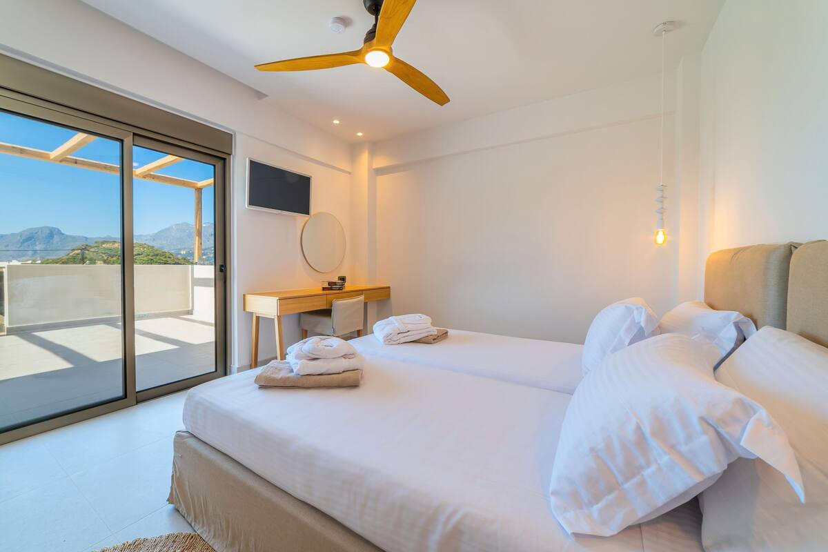 A modern hotel room with a large bed, a desk, and a view of the outdoors.
