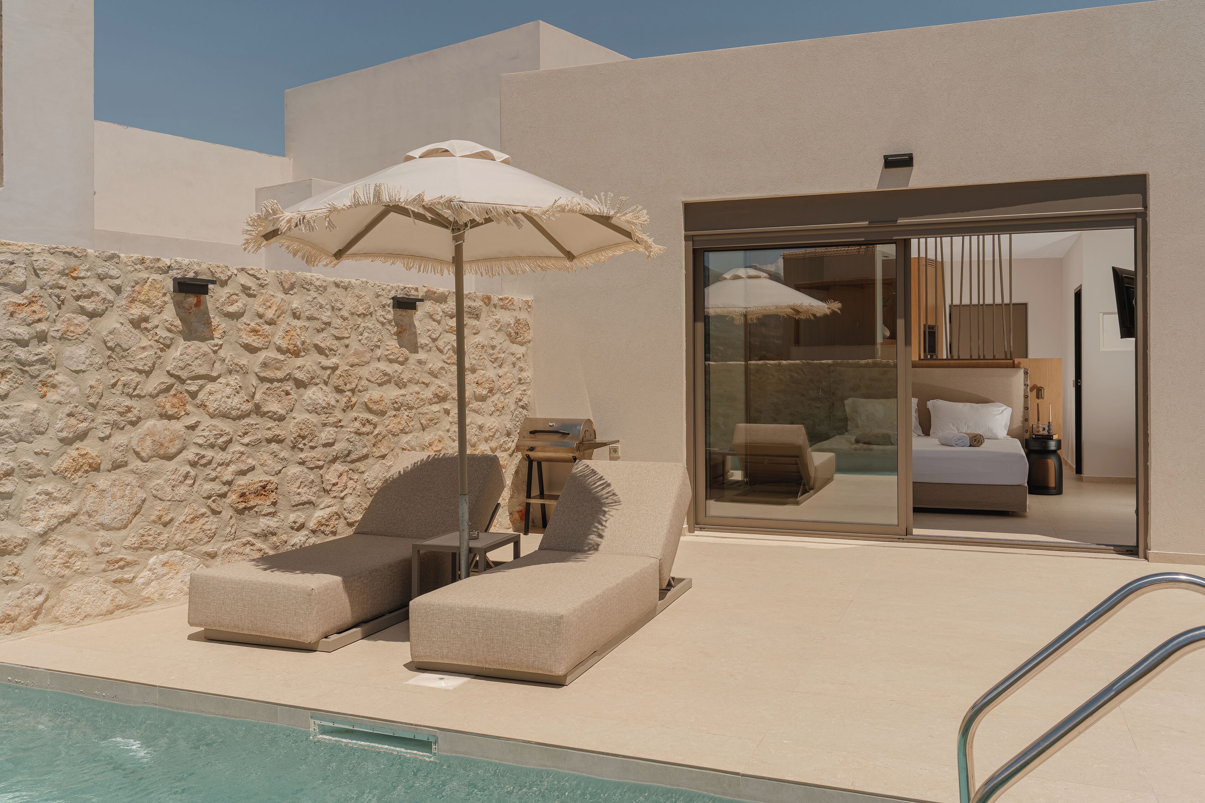Ein modernes Hotelzimmer mit Pool, einer Steinwand und einer Glastür zum Schlafzimmer.