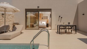 A modern outdoor pool area with lounge chairs, a table, and a glass door leading to a bedroom. - Increteblue Suites (Agios Vasileios)