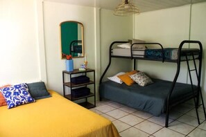 Ein Schlafsaalzimmer mit Etagenbetten, einem Schreibtisch mit Stuhl und einem Spiegel an der Wand.