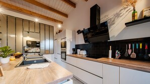 A modern kitchen with wooden beams, a black backsplash, and stainless steel appliances.