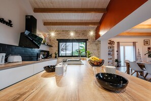 A modern kitchen with a wooden countertop, black appliances, and a large window.