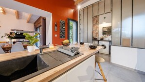 A modern kitchen with a black sink, wooden countertop, and a dining area with a table and chairs.