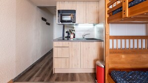 Uma cozinha compacta com micro-ondas, pia e armários de madeira.