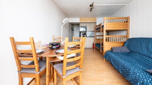 Espaço compacto com área de refeições, cozinha compacta e beliches.