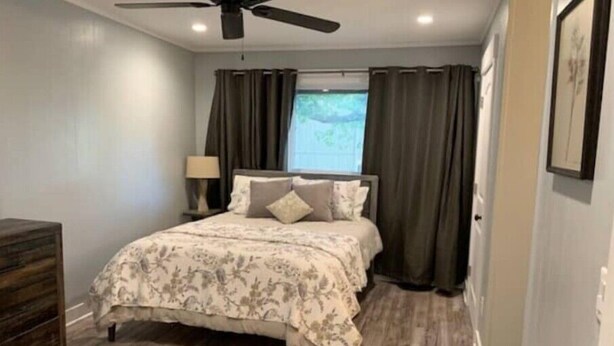 Ein Schlafzimmer mit Bett, Deckenventilator, Nachttisch mit Lampe und Kommode.