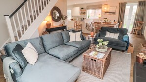 A modern living room with a grey sectional sofa, a coffee table, and a staircase. - Driftwood Sands (Chathill)