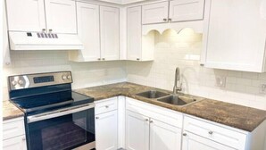 A kitchen with white cabinets, a stainless steel oven, a granite countertop, and a double sink. - BV getaway 3 bedroom style

 (Bella Vista)