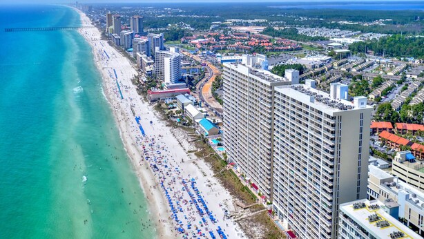 A coastal cityscape with a beach, high-rise buildings, and a clear sky. - Majestic Beach Towers I by Southern Vacation Rentals (Panama City Beach)