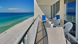 A balcony with a view of the beach and ocean, white wicker chairs, and a table. - Majestic Beach Towers I by Southern Vacation Rentals (Panama City Beach)